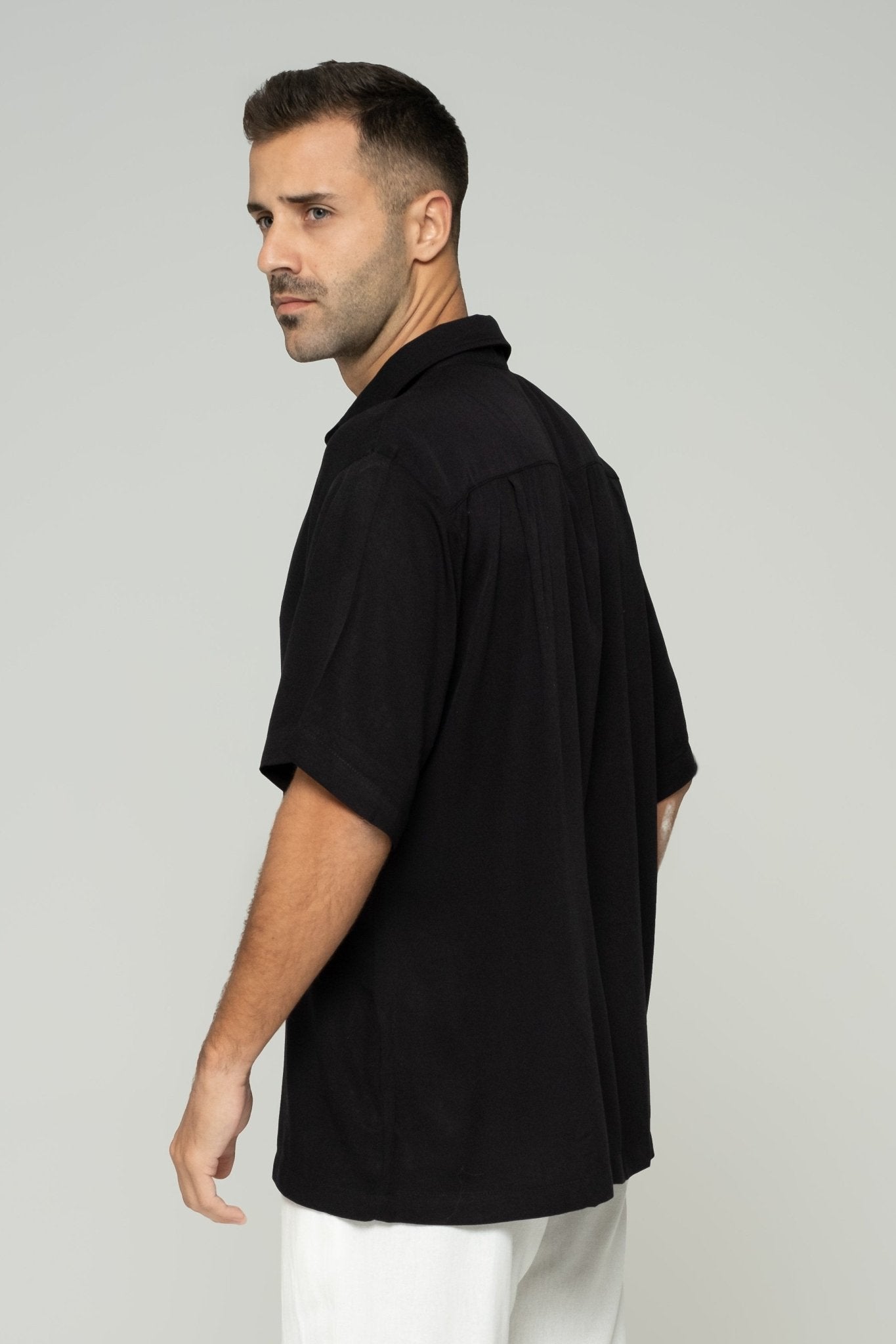 alt="Side view black Affine shirt, curved hem and short sleeve detail."