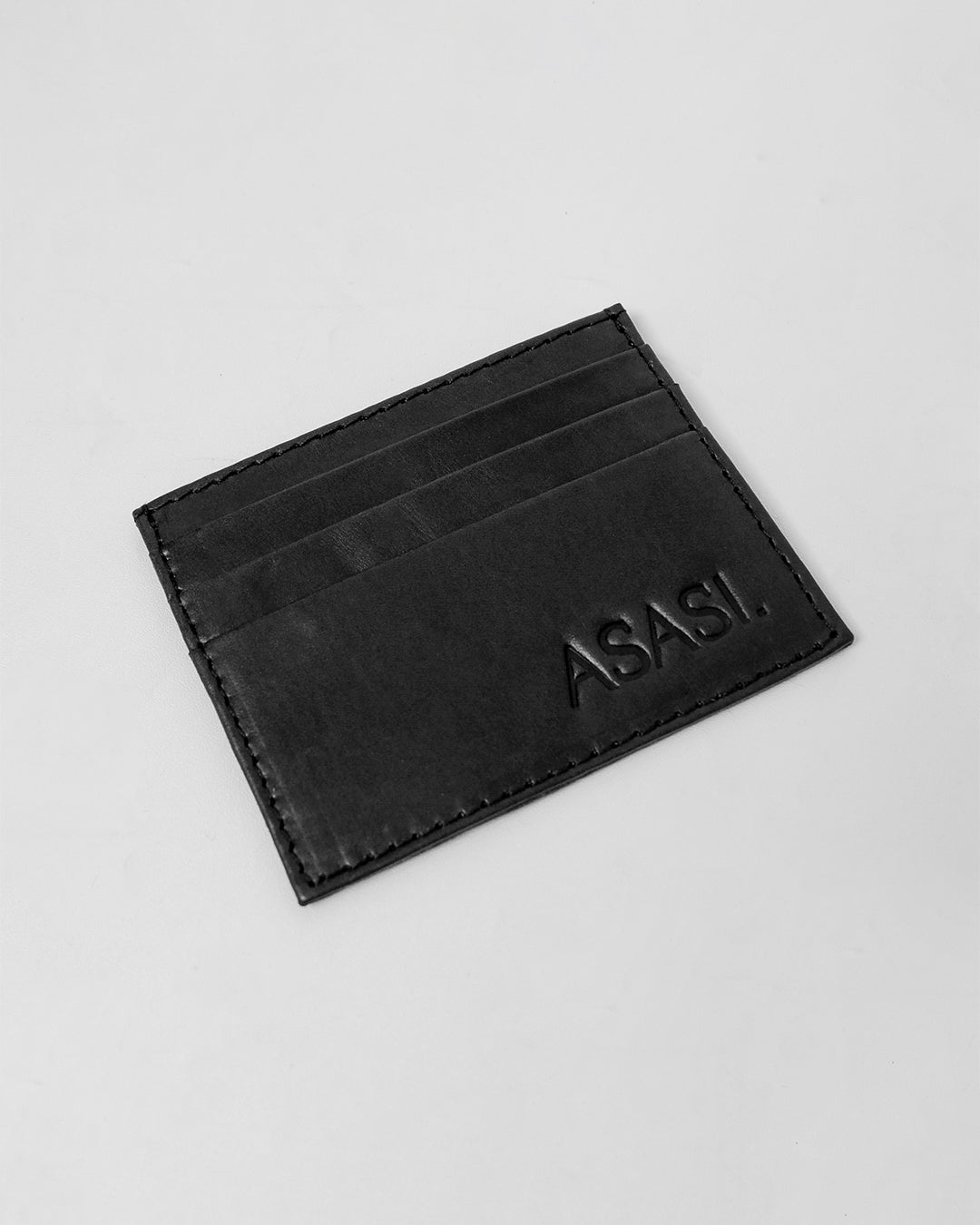 alt="Front view black leather card holder, slim profile, premium grain finish."
