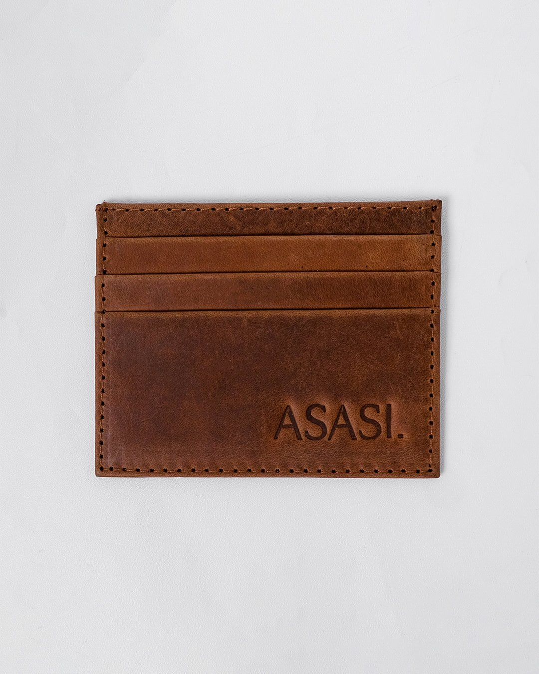 alt="Brown leather card holder with stitched seams, classic minimalist style, rich warm tone."