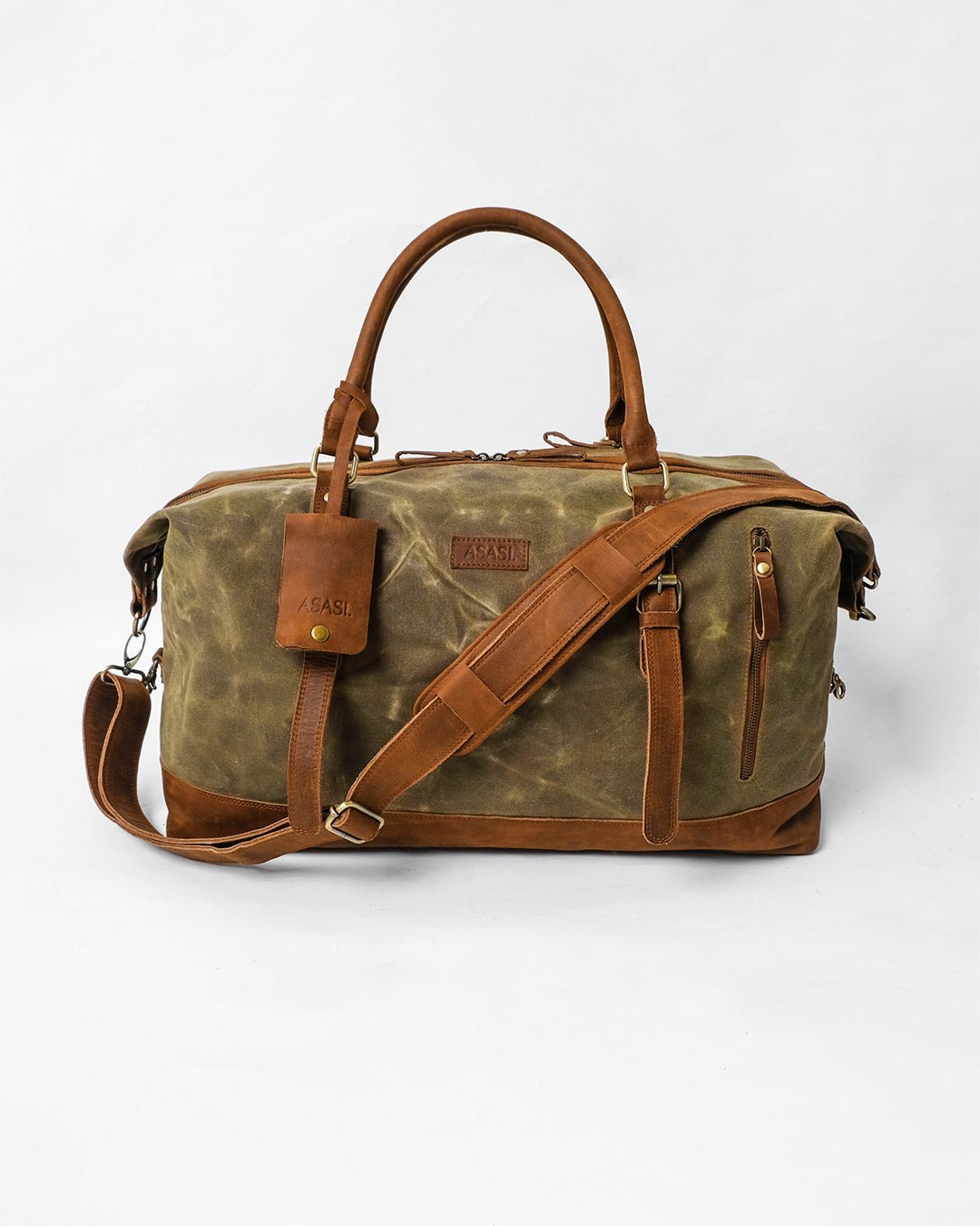 alt="Enlisted duffle bag in honey brown leather, rugged weekender with top handles and brass hardware."