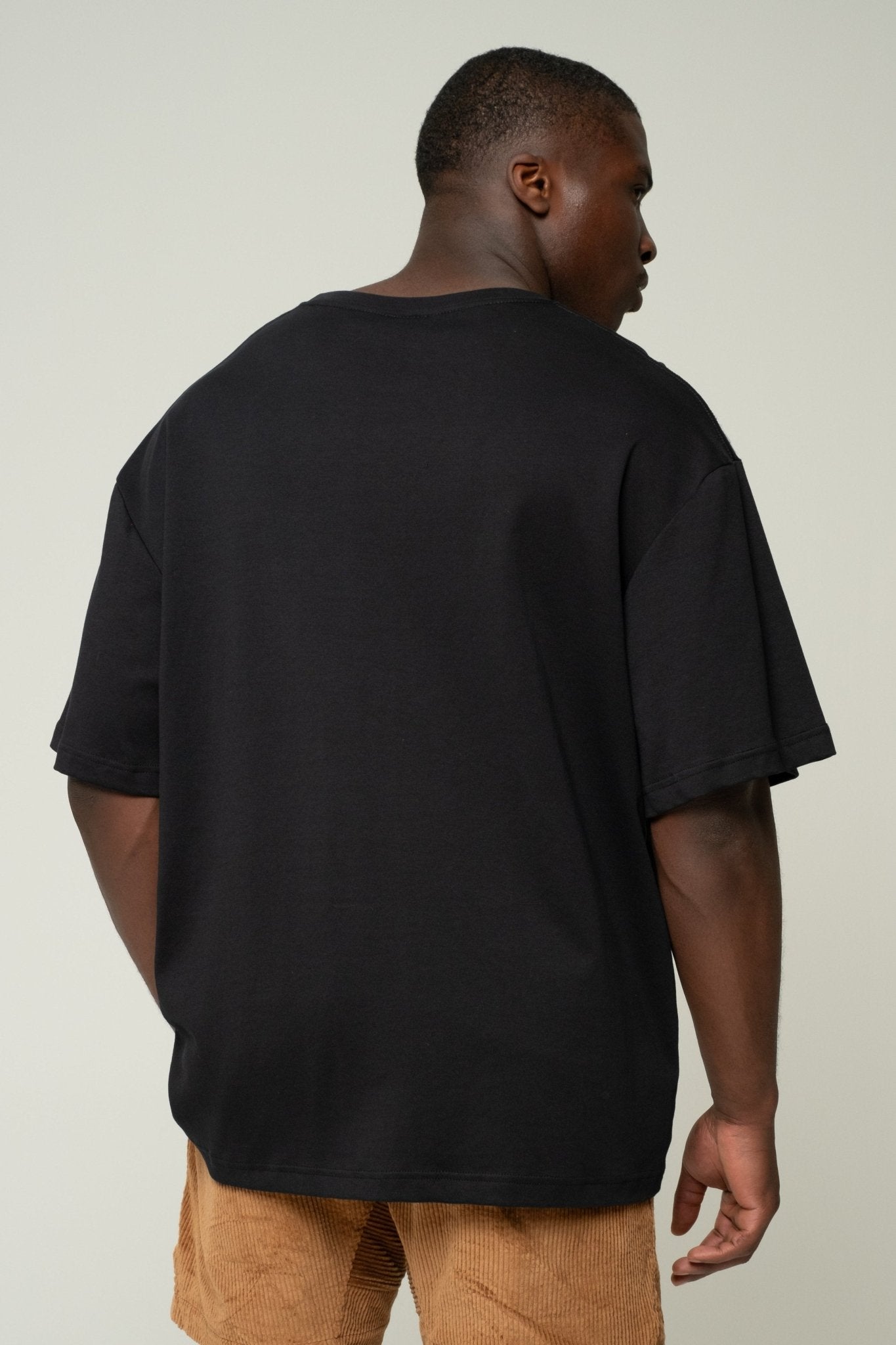 alt="Front view black Kavash t‑shirt, dropped shoulder, relaxed silhouette."