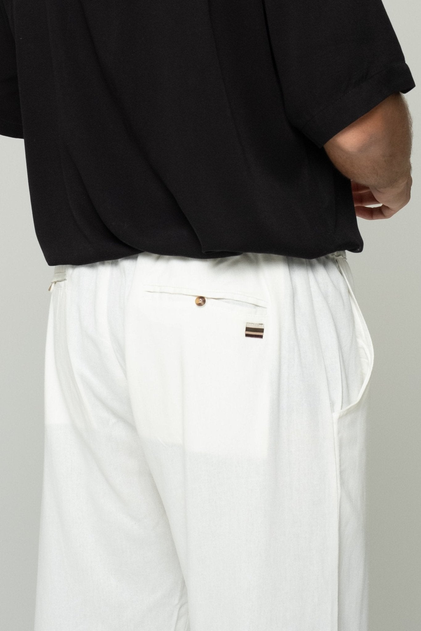 alt="Detail close-up of bone linen pants waist tie and fabric weave texture."