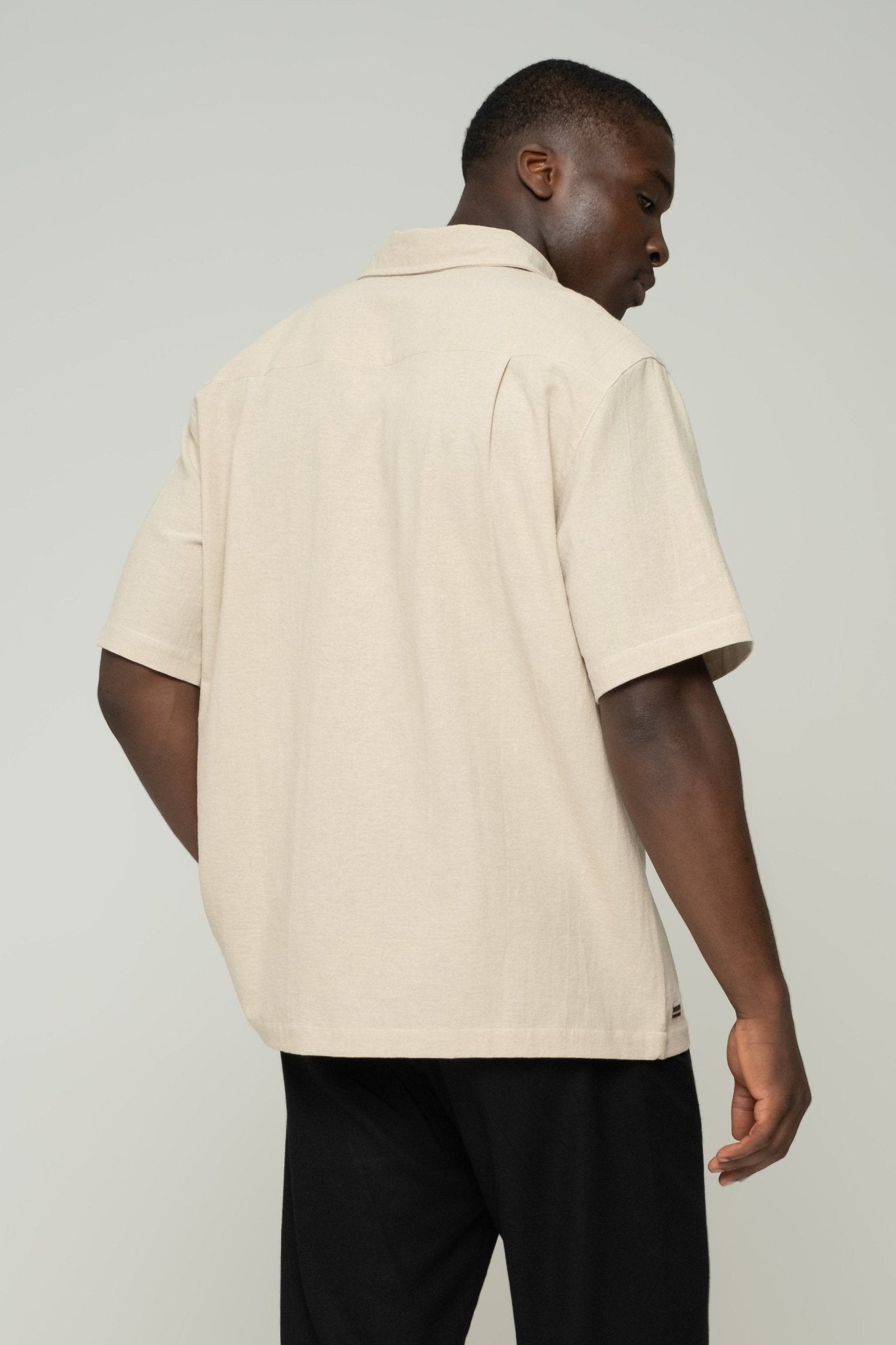 alt="Side profile beige Hearthstone origin shirt, straight hem and sleeve detail."