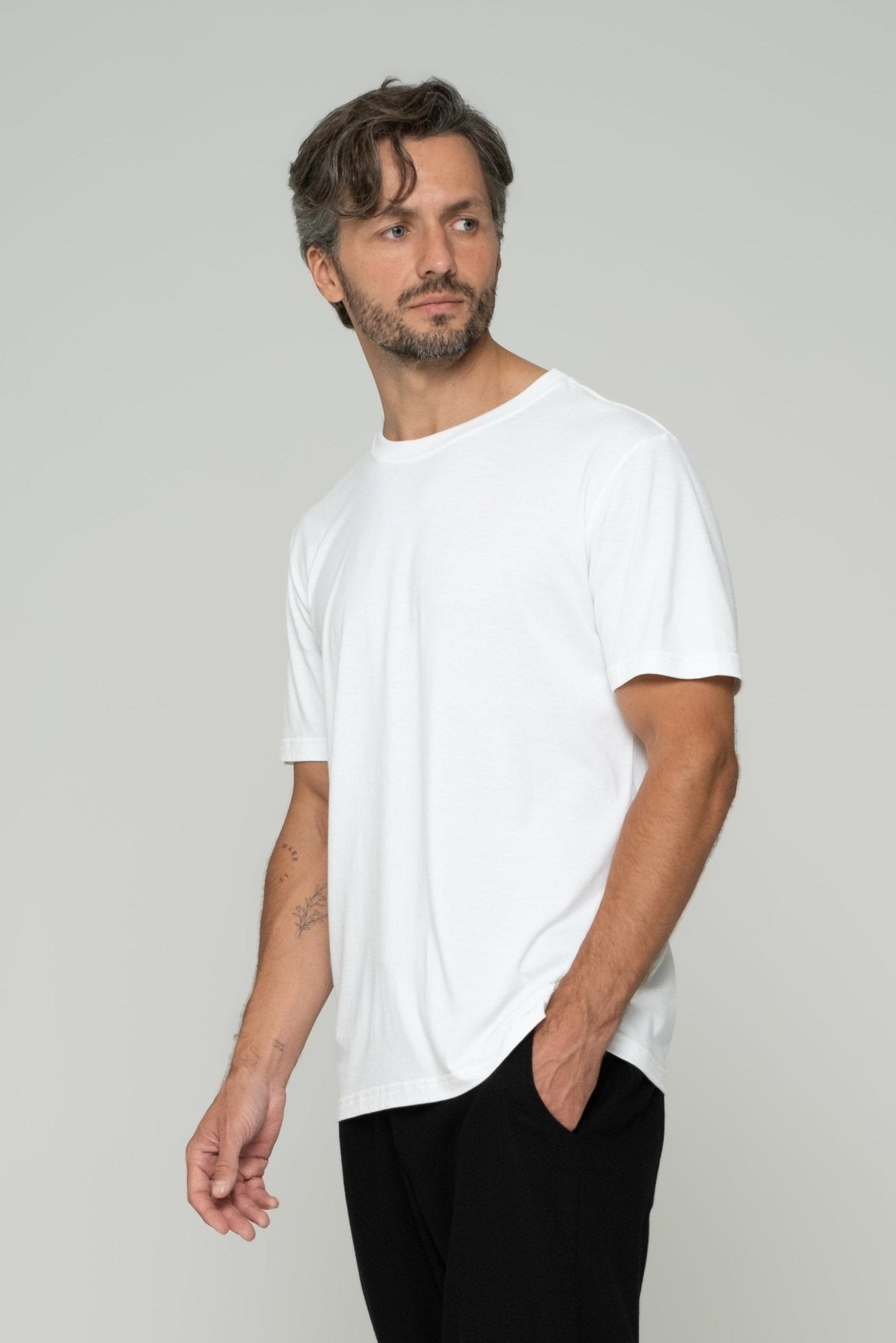 alt="Front view off‑white Vāyu t‑shirt, regular fit and curved hem."