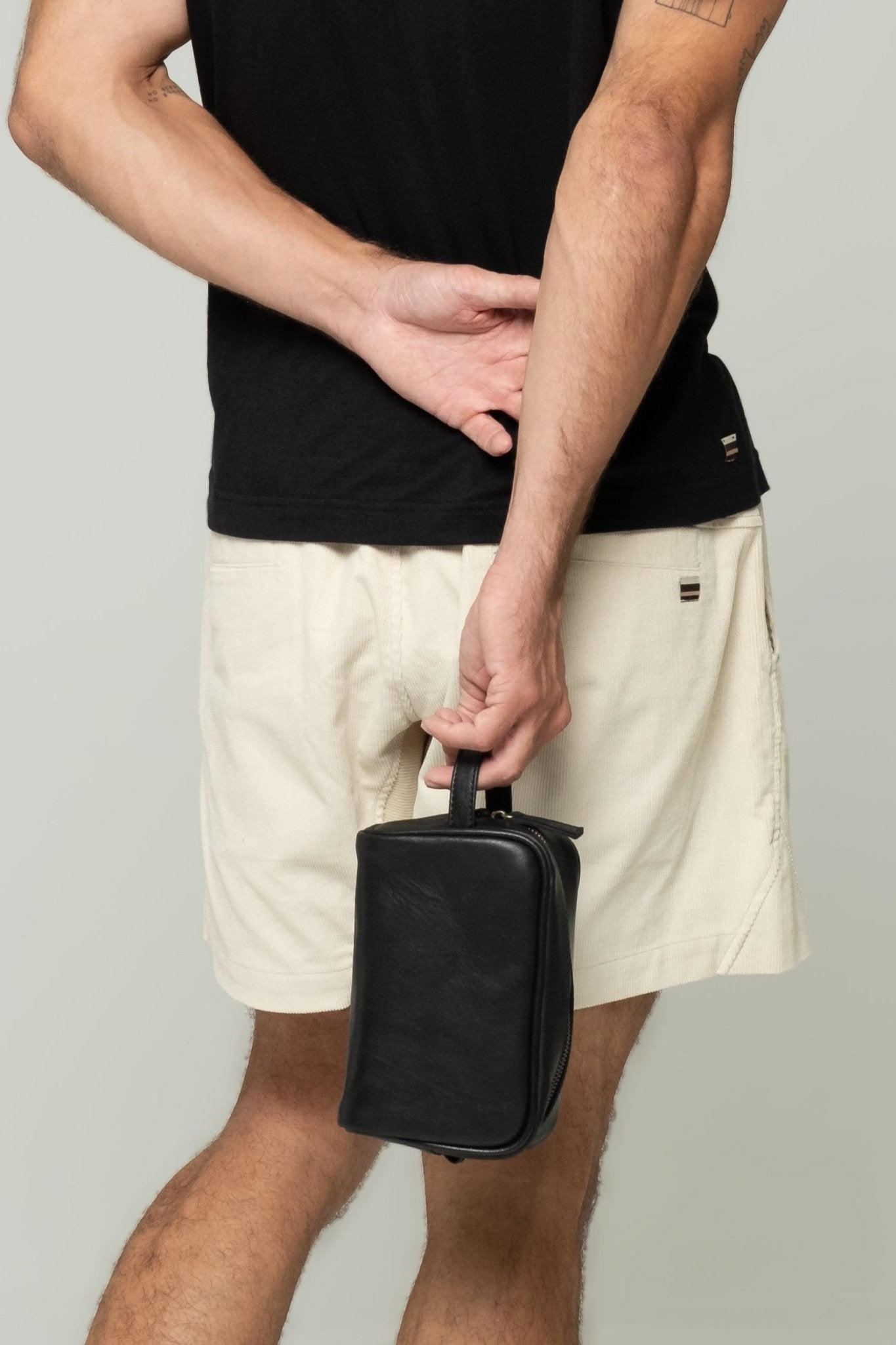 alt="Black leather wash bag, compact toiletry kit with sturdy zipper and smooth finish."