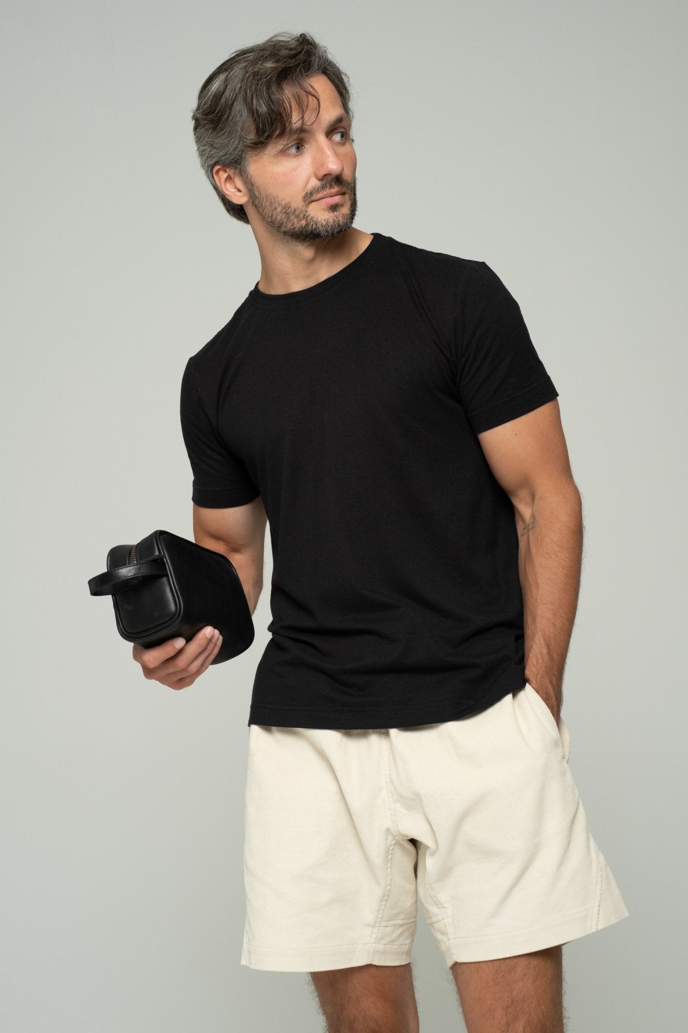 alt="Wash bag in raven black leather, rectangular toiletry pouch with zip closure, front view."